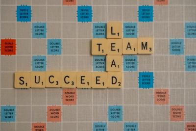 A scroabble board with the words: Team, Succeed, Lead